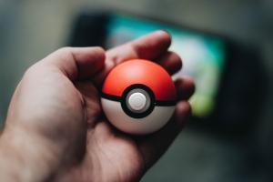 Pokémon ball in hand, Nintendo Switch in background out of focus