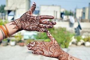 one hand painting henna art designs onto another hand