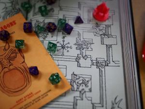 dice on a hand drawn map and first edition of RPG game Dungeons & Dragons