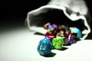 White dice bag with multicolored roleplaying dice falling out.