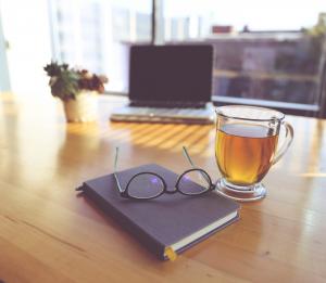 tea, journal, glasses and laptop on table