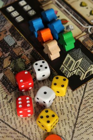 Six assorted dice with six assorted meeples on a city game board.